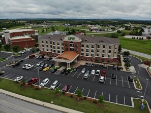 A hotel with a parking lot, a fountain, and a large building with a flat roof. - Holiday Inn Express & Suites Glenpool-Tulsa South by IHG (Glenpool)