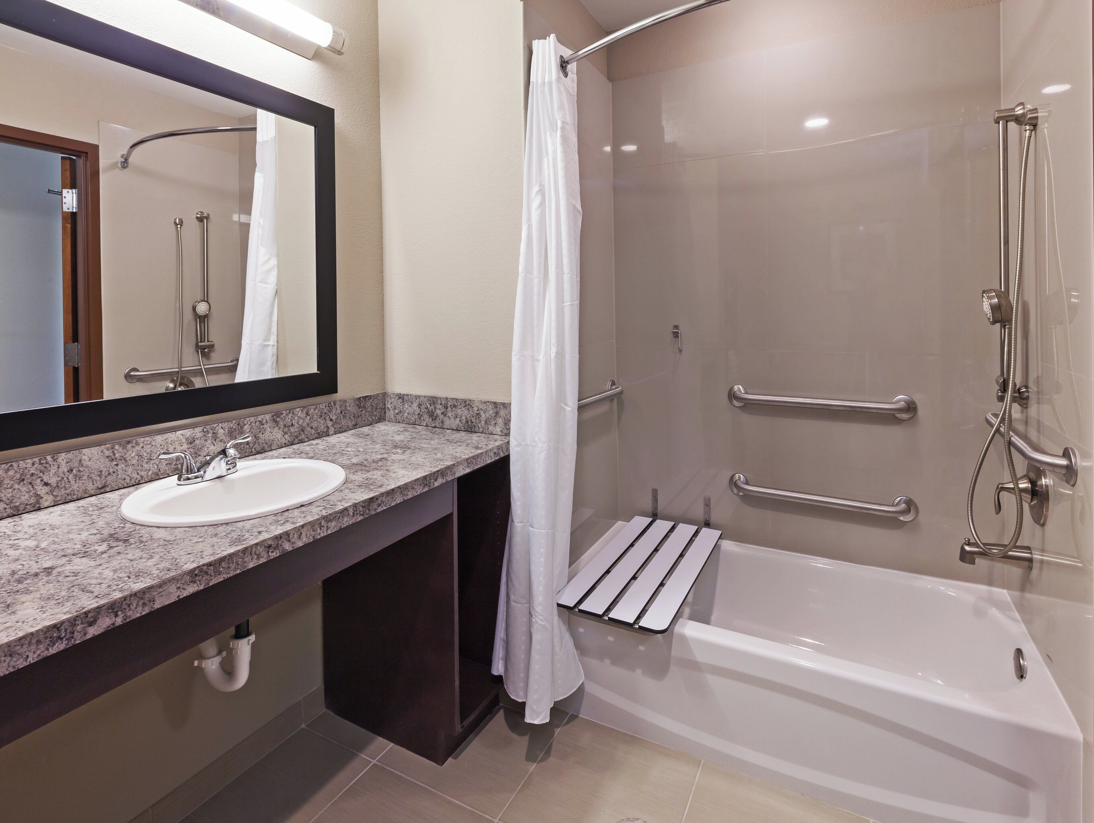A modern bathroom with a sink, mirror, shower, and bathtub.