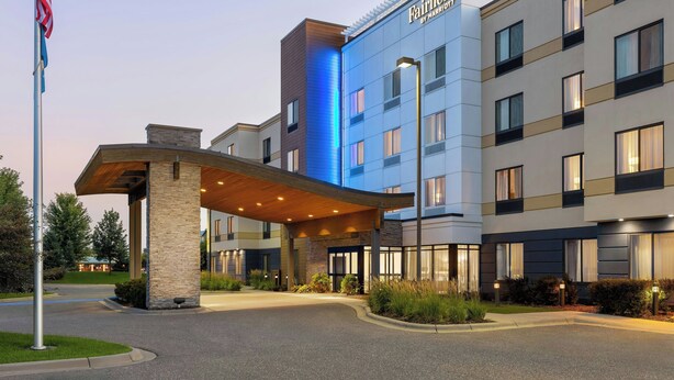 Een meerhoog hotel met een opvallende ingang, een overdekte doorgang en een vlaggenmast.