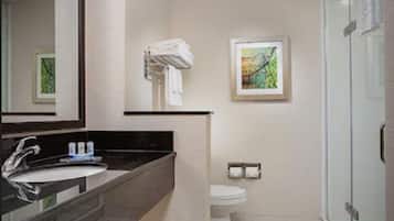 A modern bathroom with a large mirror, a sink, a toilet, and a shower area.