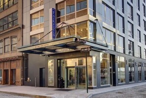 Un hotel Marriott con fachada moderna, ventanas grandes y un área de acceso cubierta.