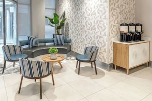 Un espace de vie moderne comprenant un canapé, des fauteuils, un coin café et une plante en pot.
