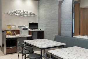 Um restaurante moderno com mesas de mármore, uma obra de arte com tema de peixes e um balcão com uma impressora.
