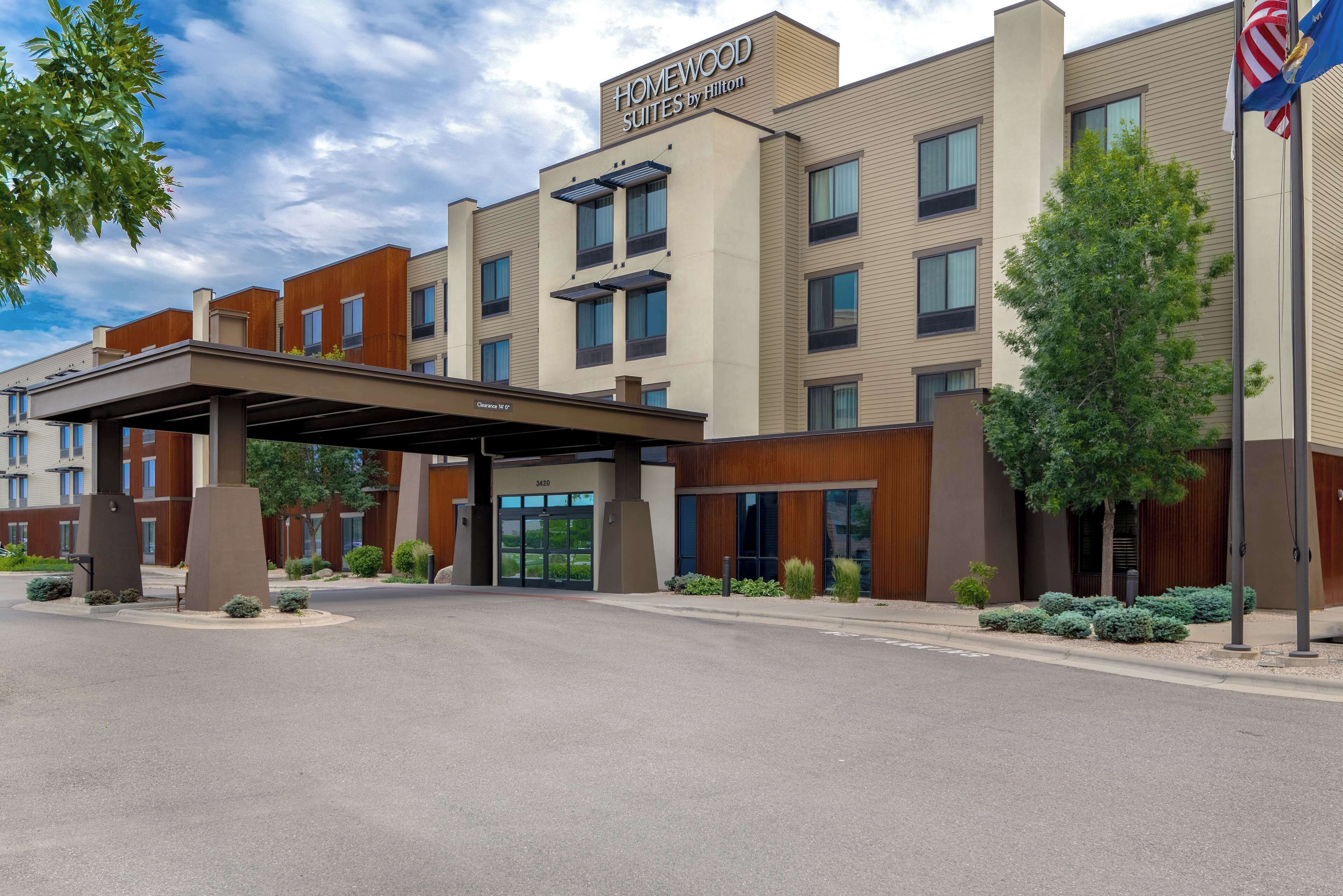 A modern hotel with a covered entrance, multiple floors, and a flag.