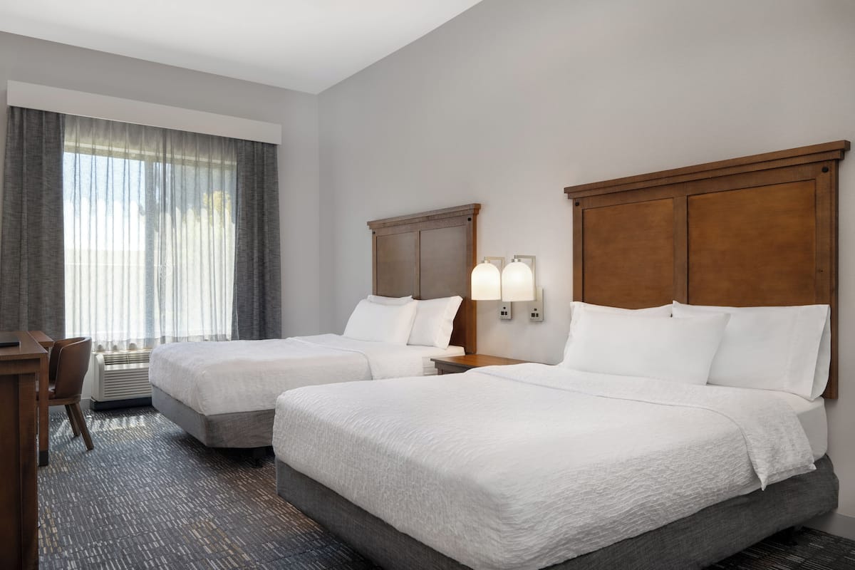 Een hotelkamer met twee bedden, een bureau en een stoel.