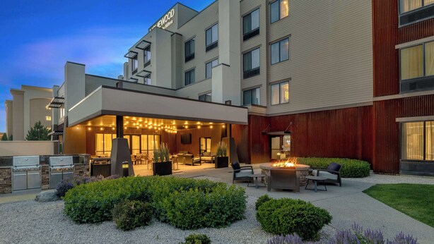A hotel with a well-lit outdoor patio area featuring a fire pit, seating, and a variety of plants. - Homewood Suites By Hilton Billings, MT (Billings)