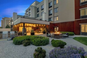 Un hotel con un patio exterior bien iluminado que cuenta con una fogata, asientos y una variedad de plantas.