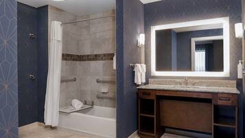 A modern bathroom with a bathtub, shower, and vanity with a large mirror.