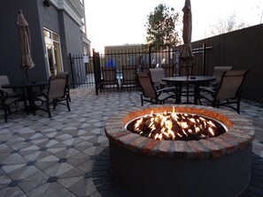 An outdoor patio with a fire pit, seating area, and a building in the background. - Holiday Inn Covington by IHG (Covington)
