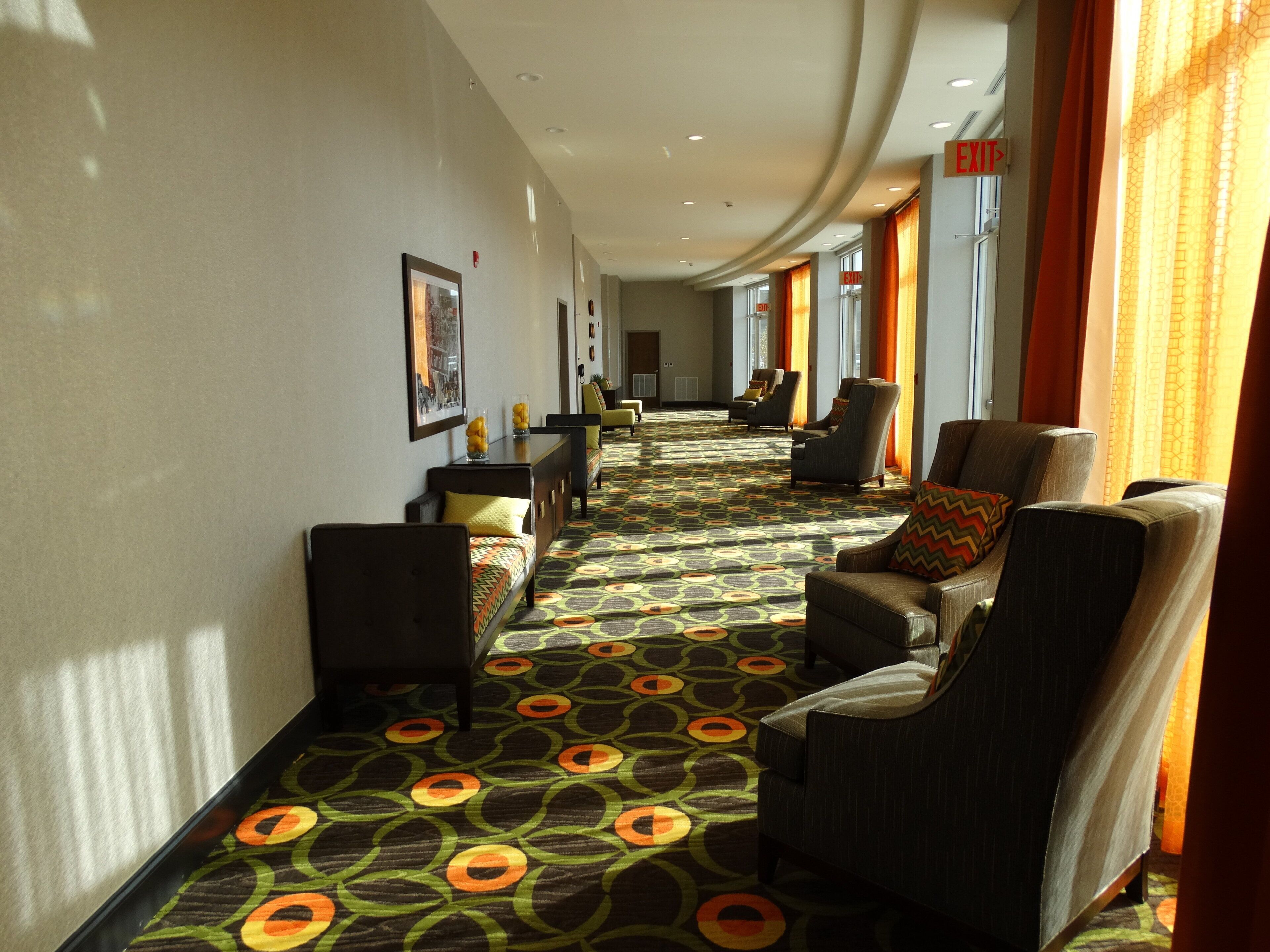 Un'hall dell'hotel con una moquette decorata, zone relax e vista sul corridoio.