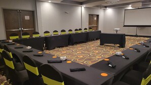 A conference room with a long table, chairs, and a projector screen. - Holiday Inn Covington by IHG (Covington)