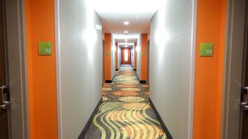 Un couloir d’hôtel avec les portes numérotées 512 et 515, recouvert d’un tapis à motifs.