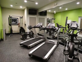 Un gimnasio con cintas de correr, bicicletas estáticas y máquinas de pesas.