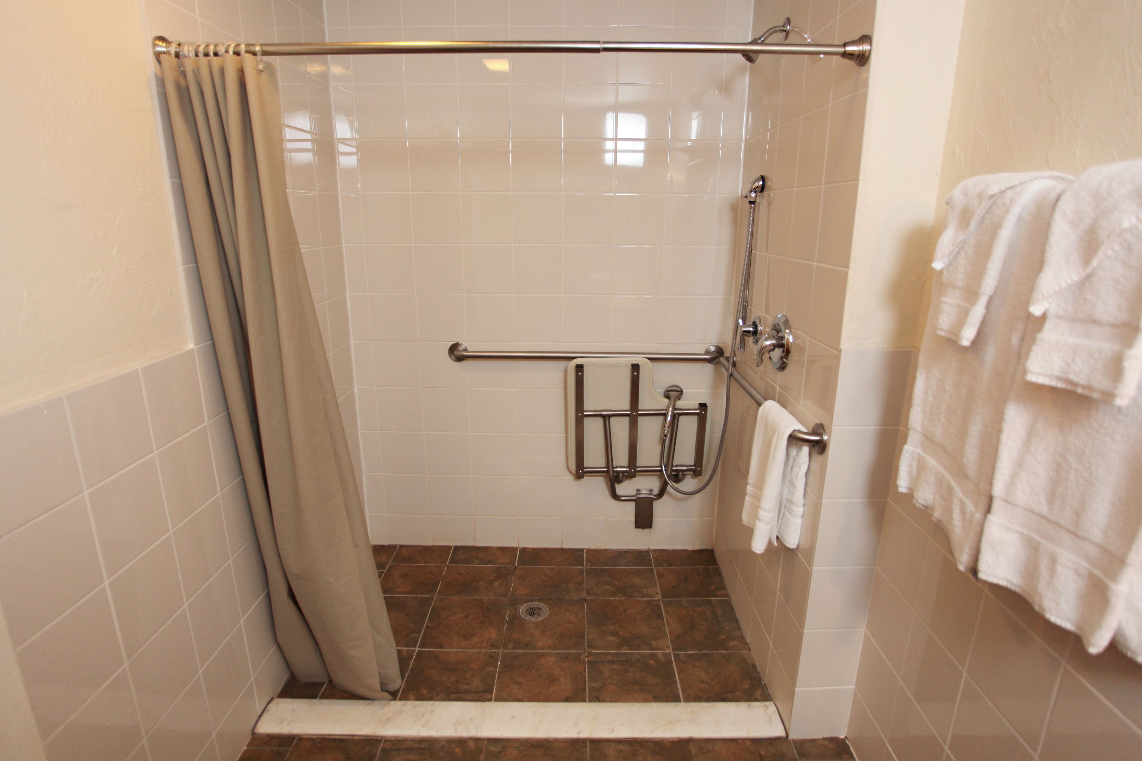 Un espace douche équipé d’une barre d’appui, d’un porte-serviettes et d’un rideau de douche.
