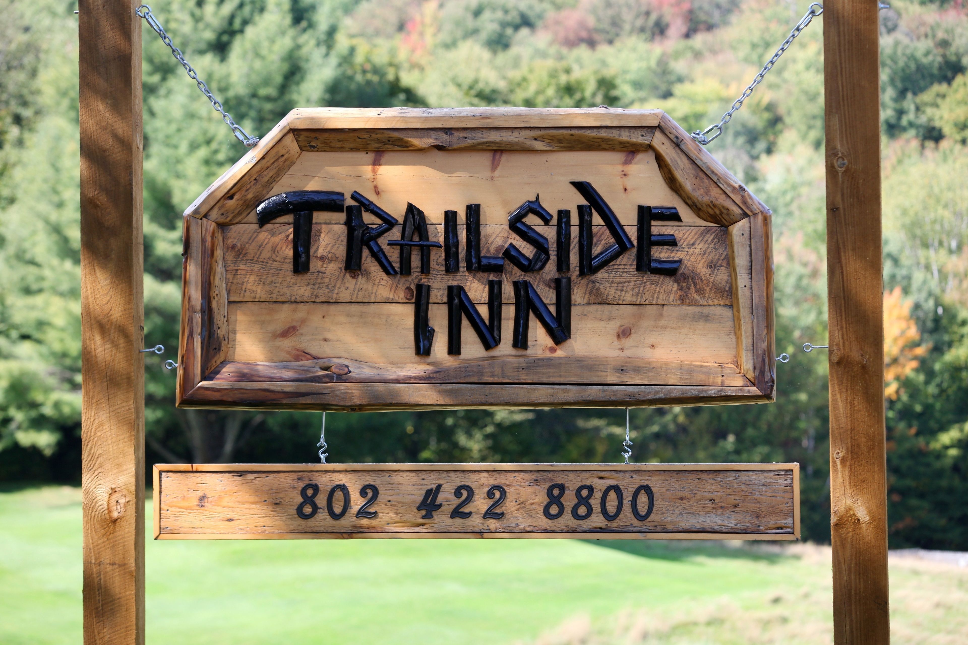 Un letrero de madera del Trailside Inn con el nombre y el número de teléfono.