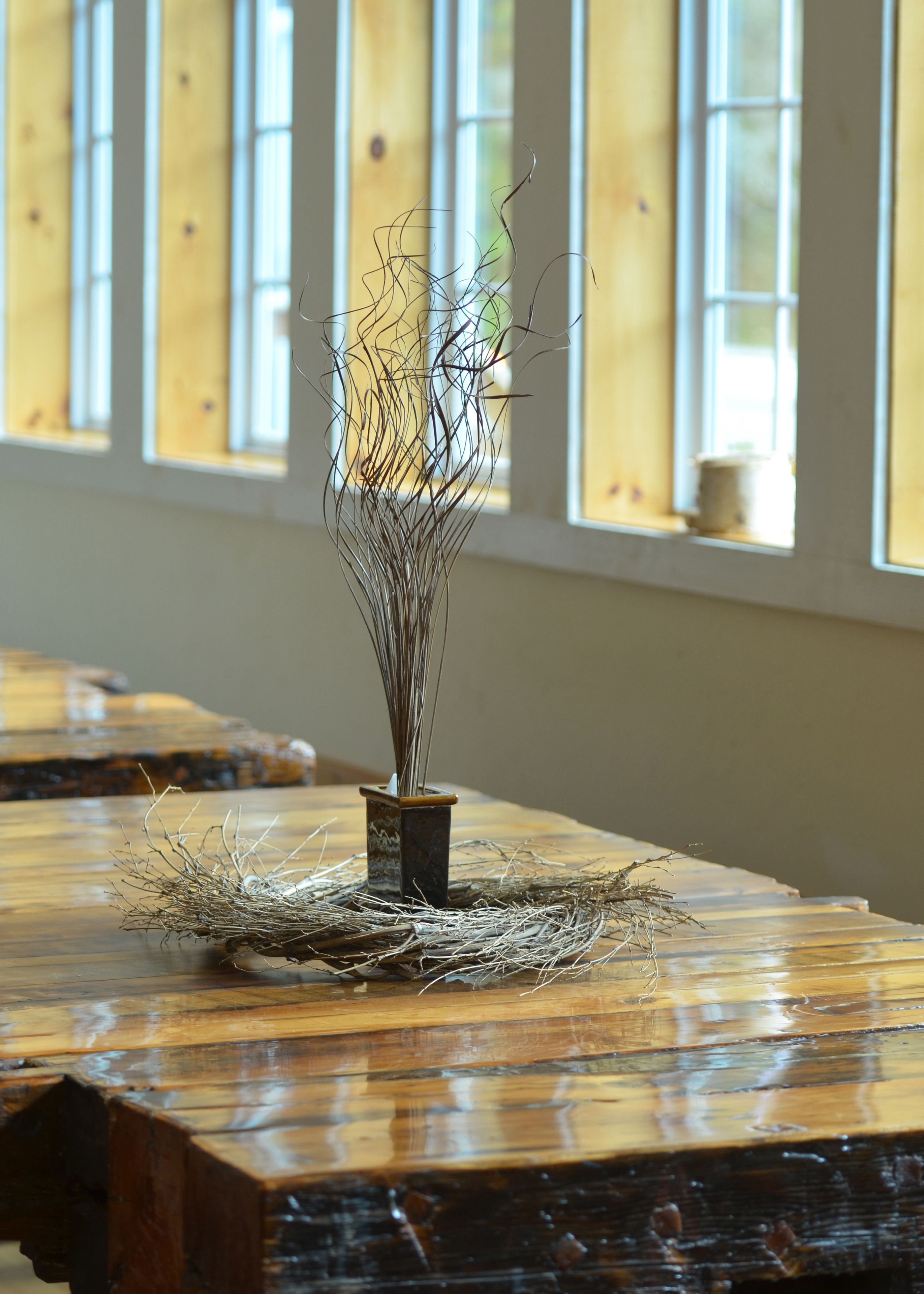 A wooden table with a vase of dried branches.