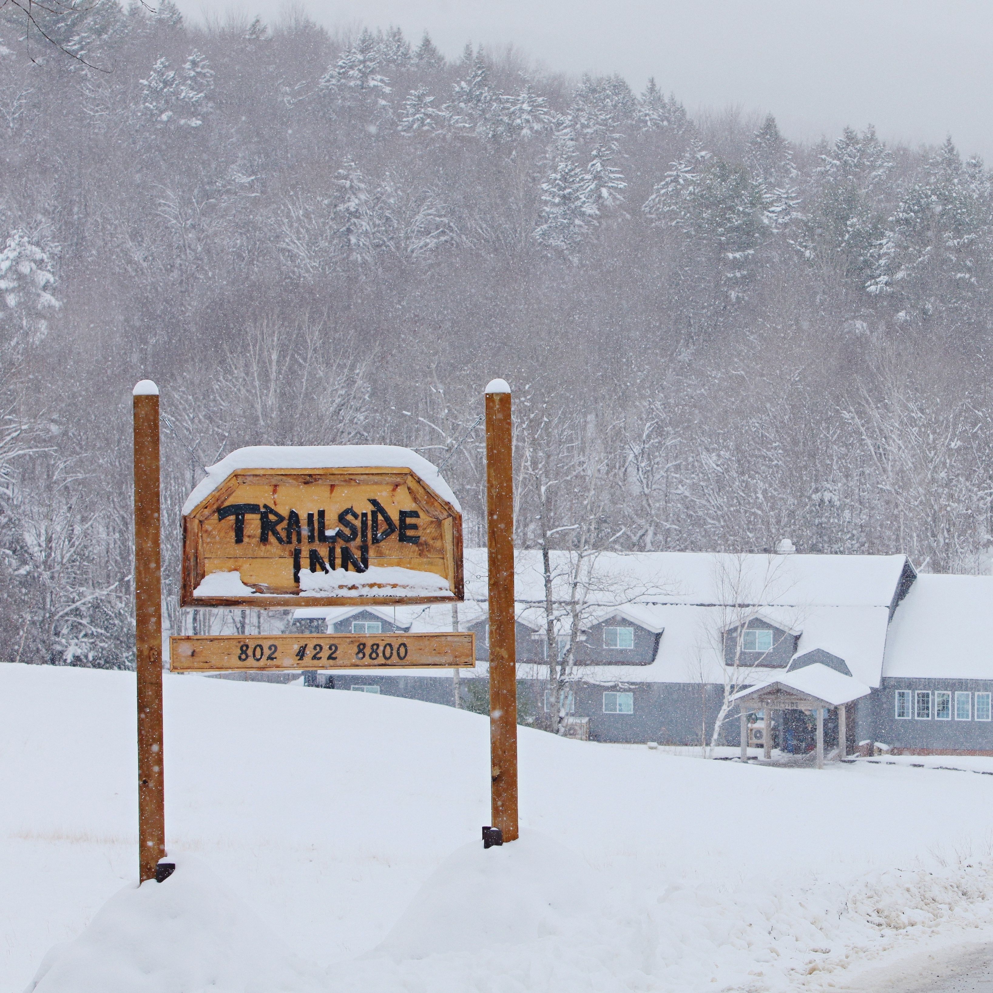 A wooden sign for the Trailside Inn with a contact number.