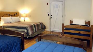 A room with two beds, a wooden headboard, a lamp, and a door.