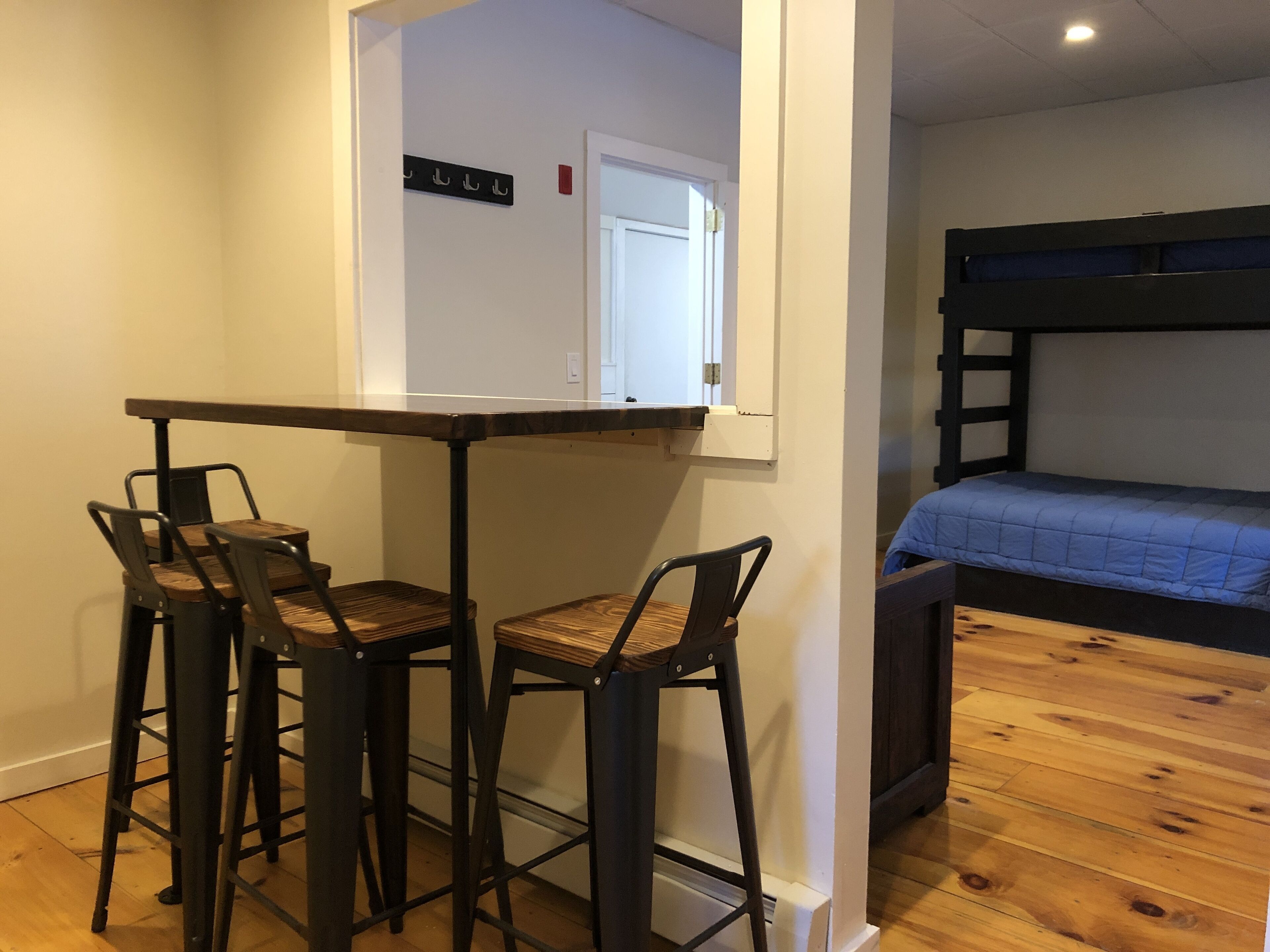A compact room with a bunk bed, a small table with two chairs, and a coat rack.