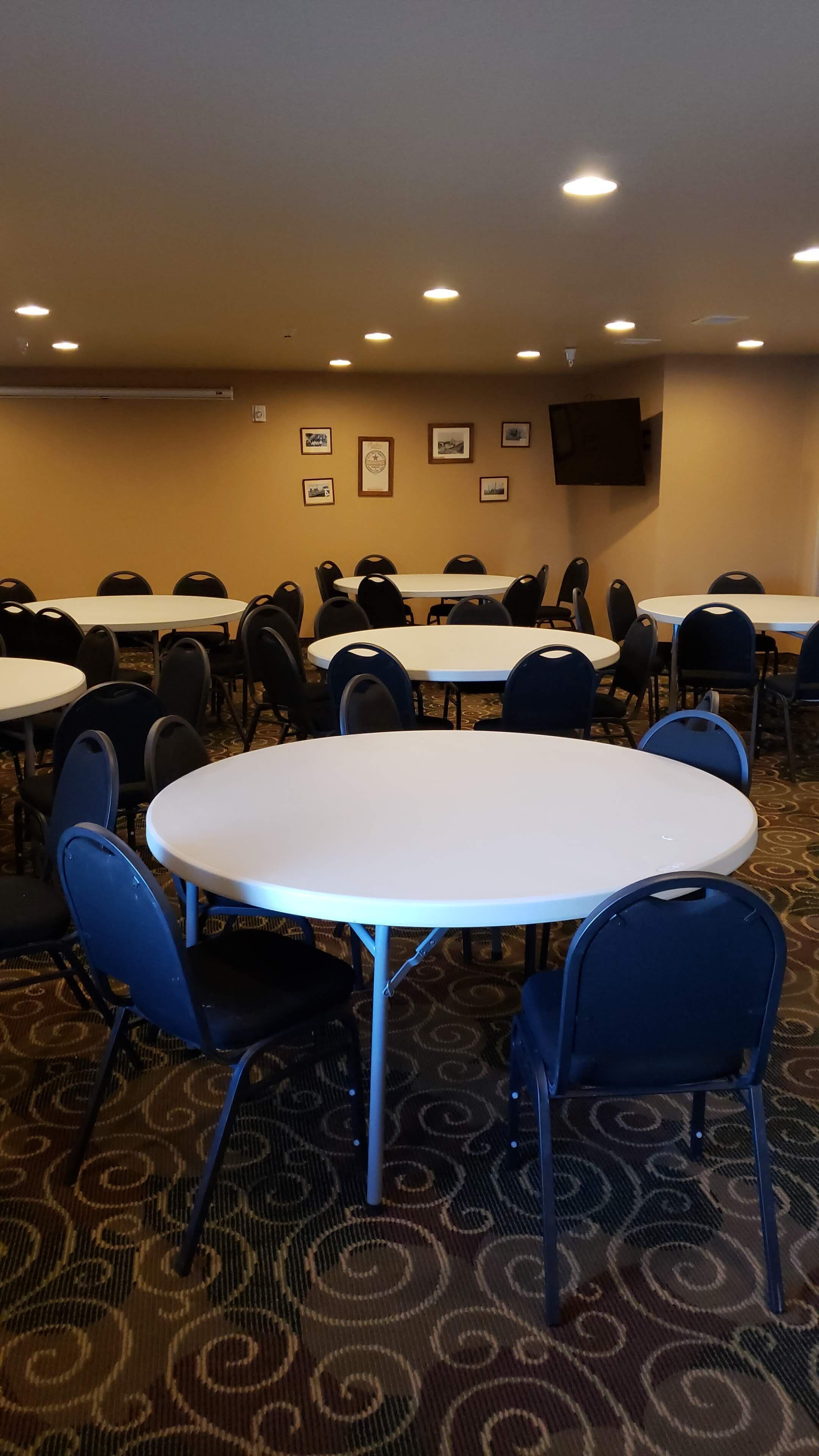 A conference room with round tables and chairs, a carpeted floor, and framed pictures on the wall.