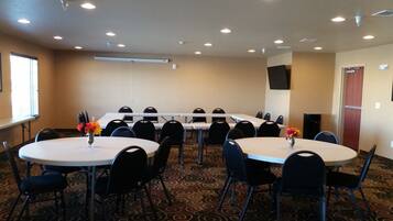 A conference room with round tables, chairs, and floral centerpieces.