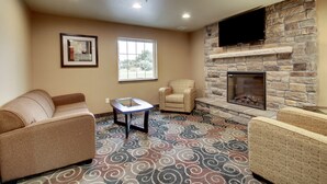 A living room with a stone fireplace, a sofa, a chair, and a television mounted on the wall.