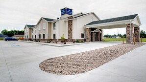 A hotel with a covered entrance, a brick facade, and a parking lot.