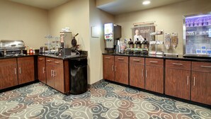 A hotel kitchen with a coffee station, a refrigerator, and a self-serve beverage machine.