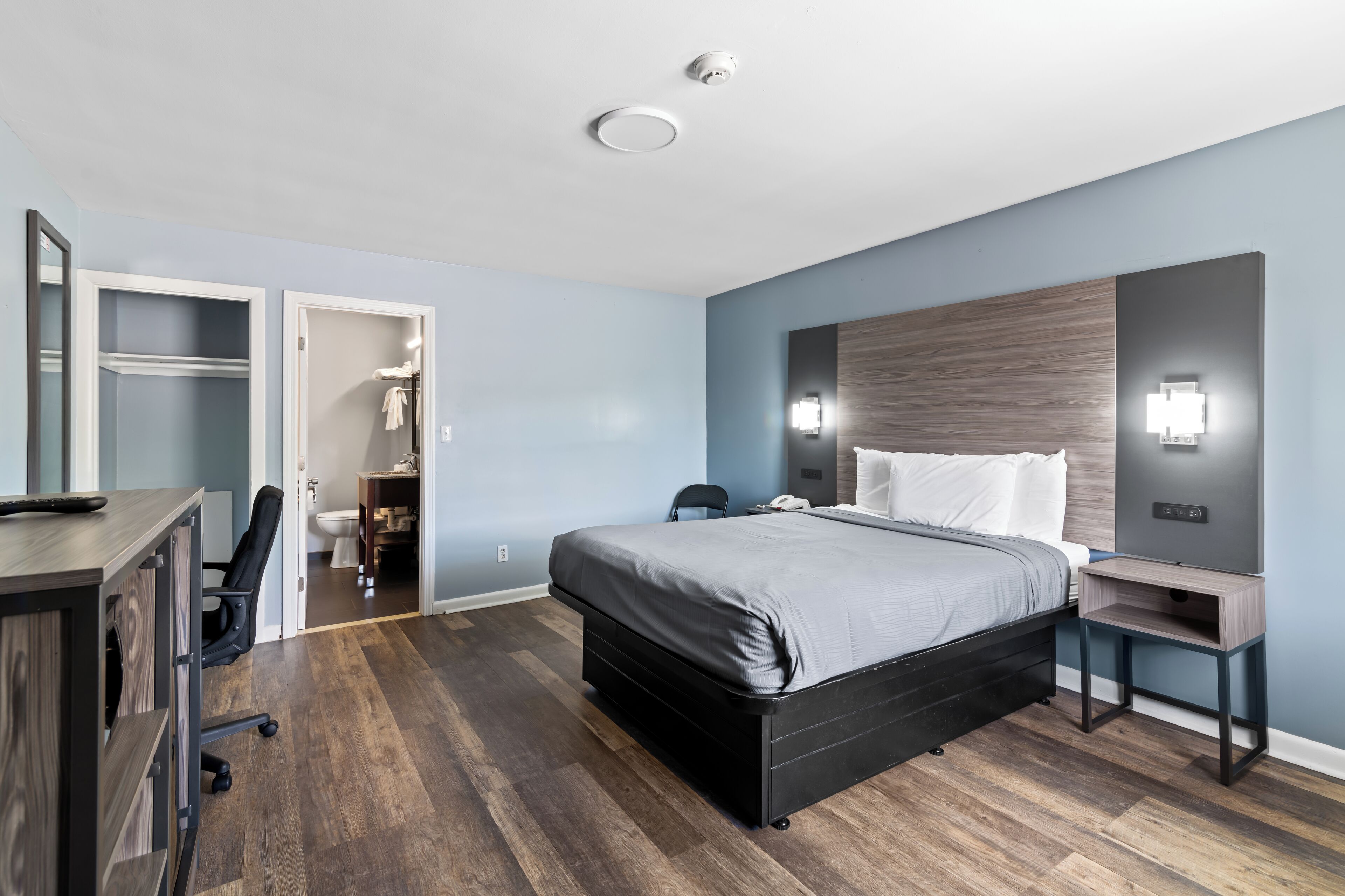 Una camera d'albergo moderna con un letto grande, una scrivania e un armadio.