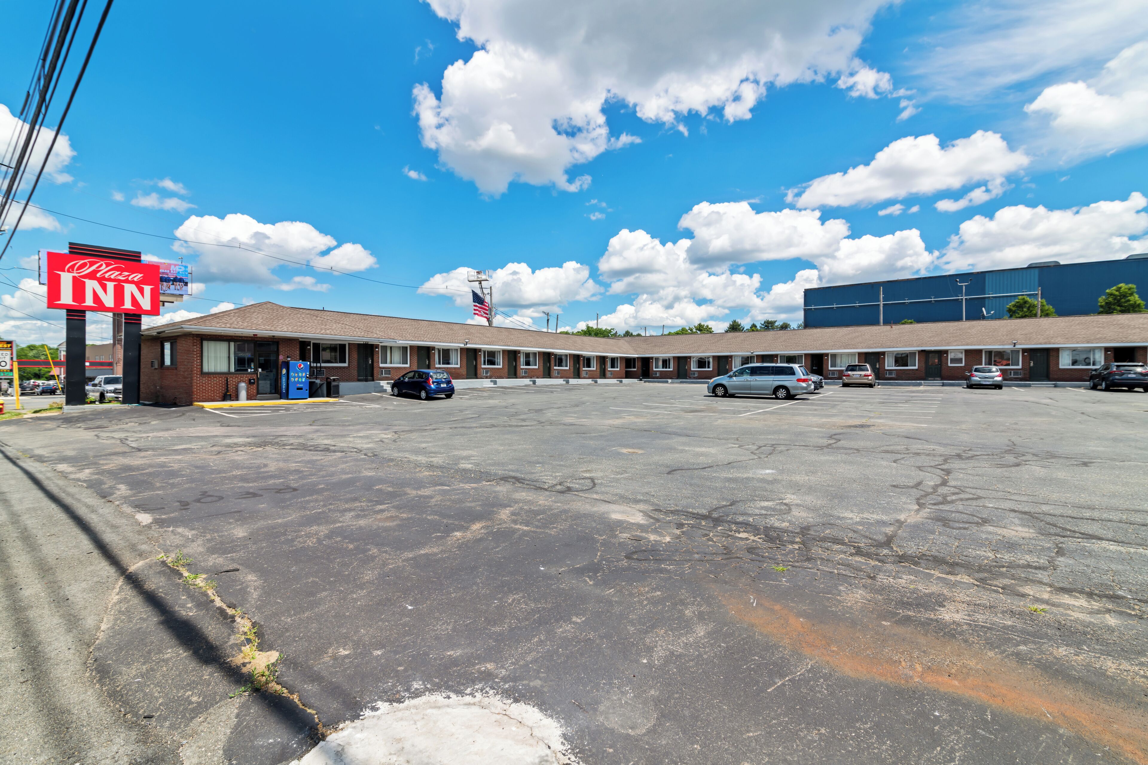 A motel with a large parking lot, a Pizza Inn sign, and a blue building in the background.