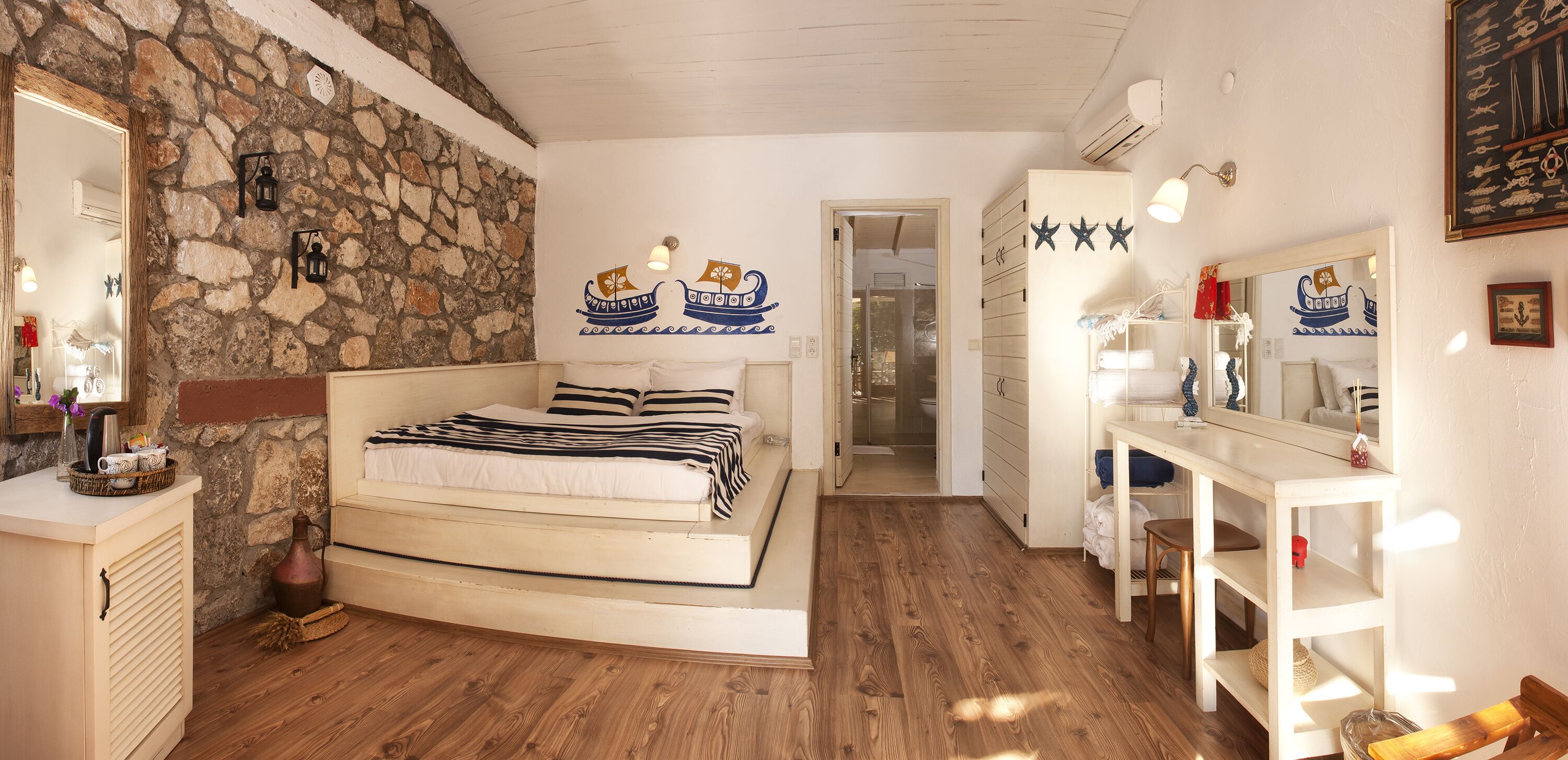 A bedroom with a stone wall, a bed, a wooden dresser, and a mirror.