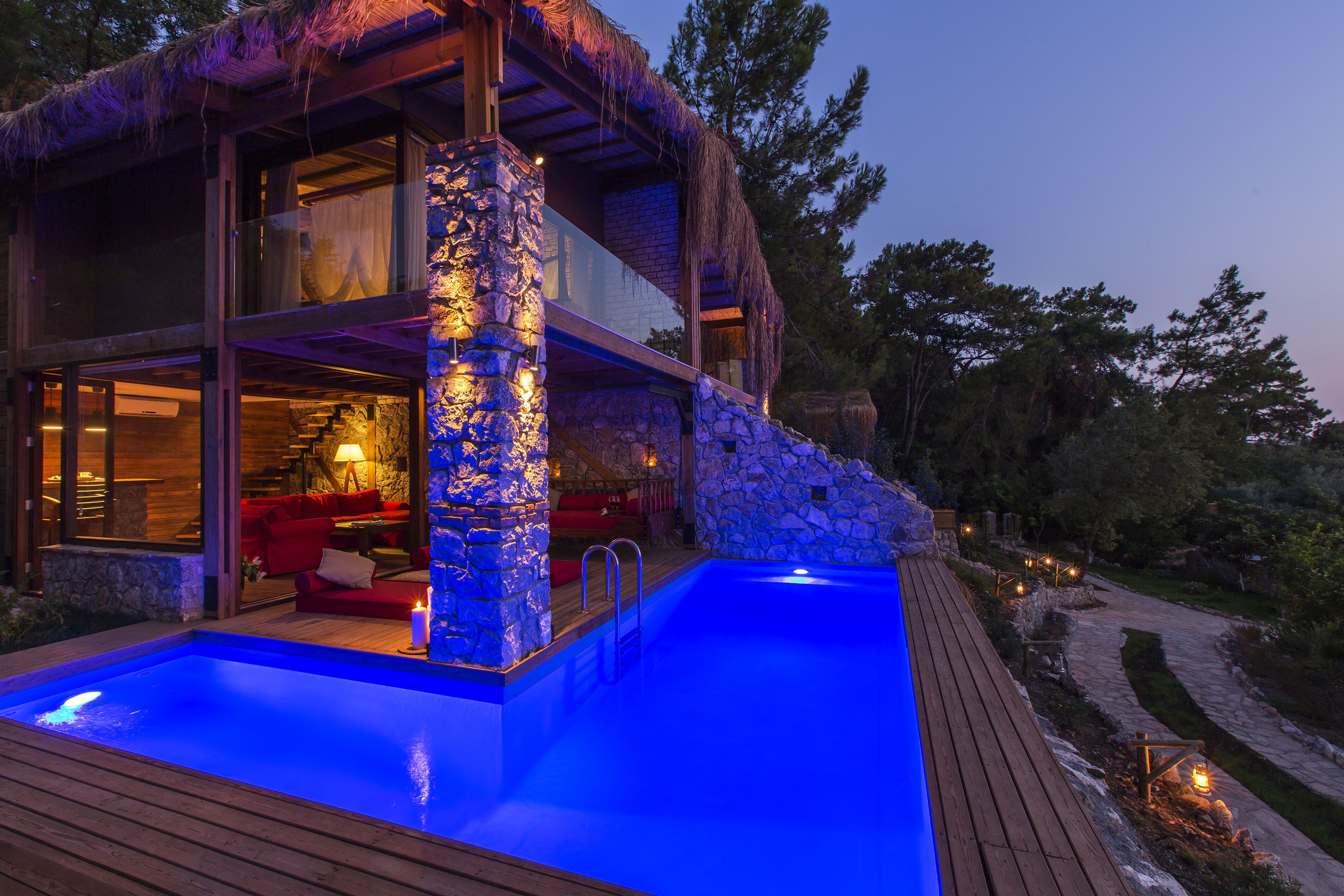 A modern house with a swimming pool, stone pillar, and a red couch.
