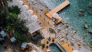 Eine Vogelperspektive zeigt ein Resort mit einer Holzterrasse, Sitzgelegenheiten im Freien und einem Pool.
