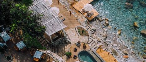 An aerial view of a resort with a wooden deck, outdoor seating, and a pool.