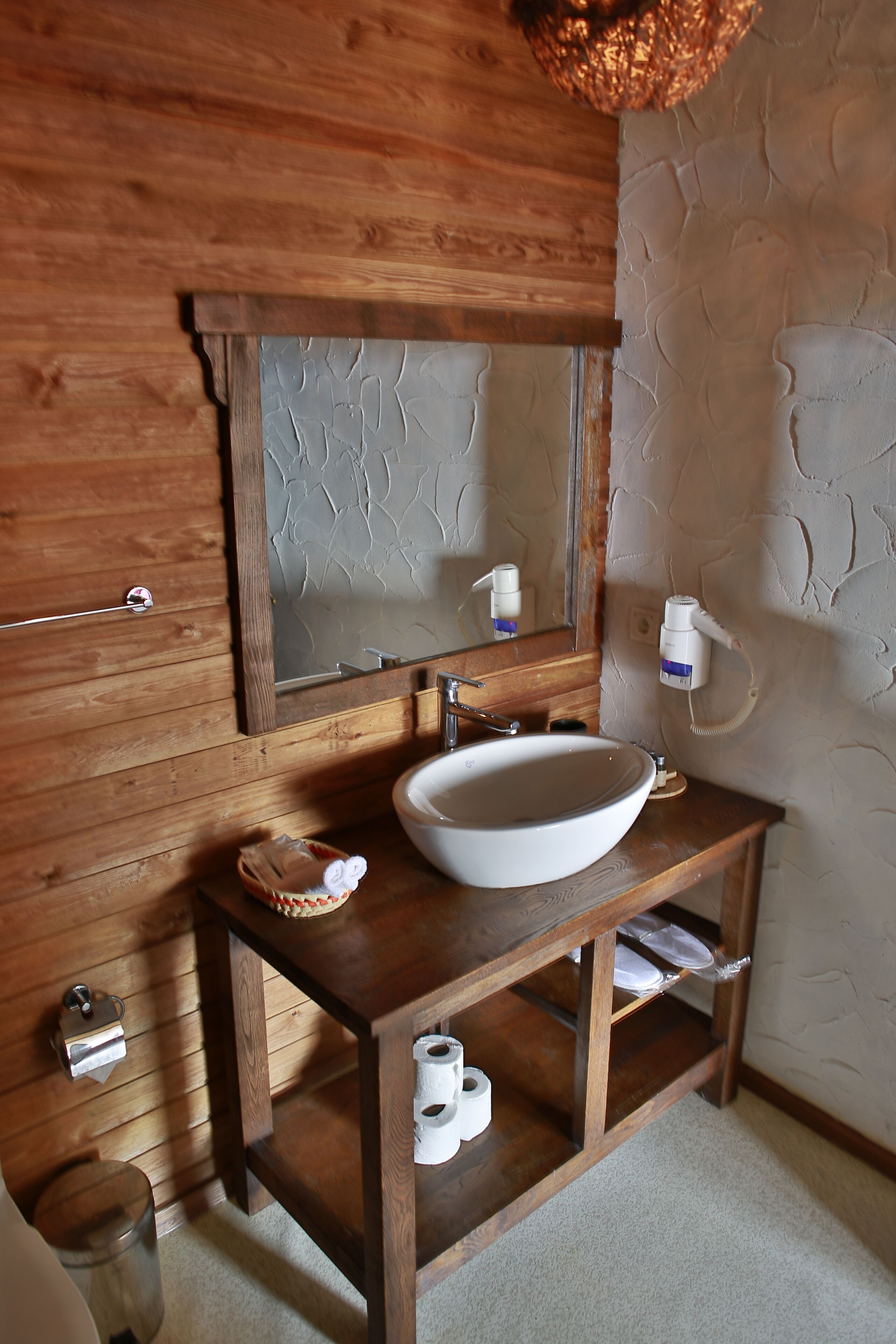 A wooden vanity with a white sink, a mirror, and a towel rack.