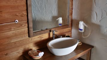 A wooden vanity with a white sink, a mirror, and a towel rack.