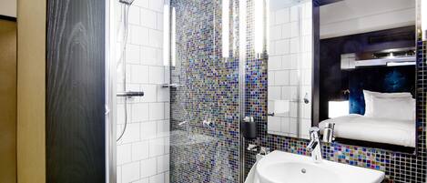A modern bathroom with a glass-enclosed shower, a white sink, and a mirror with a black frame.