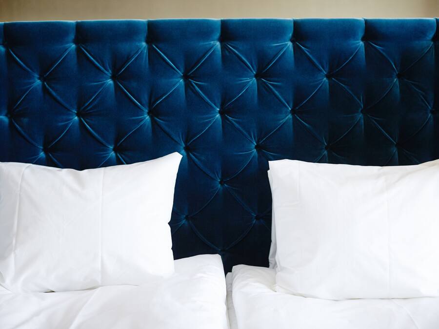 A bed with a tufted headboard and white pillows.