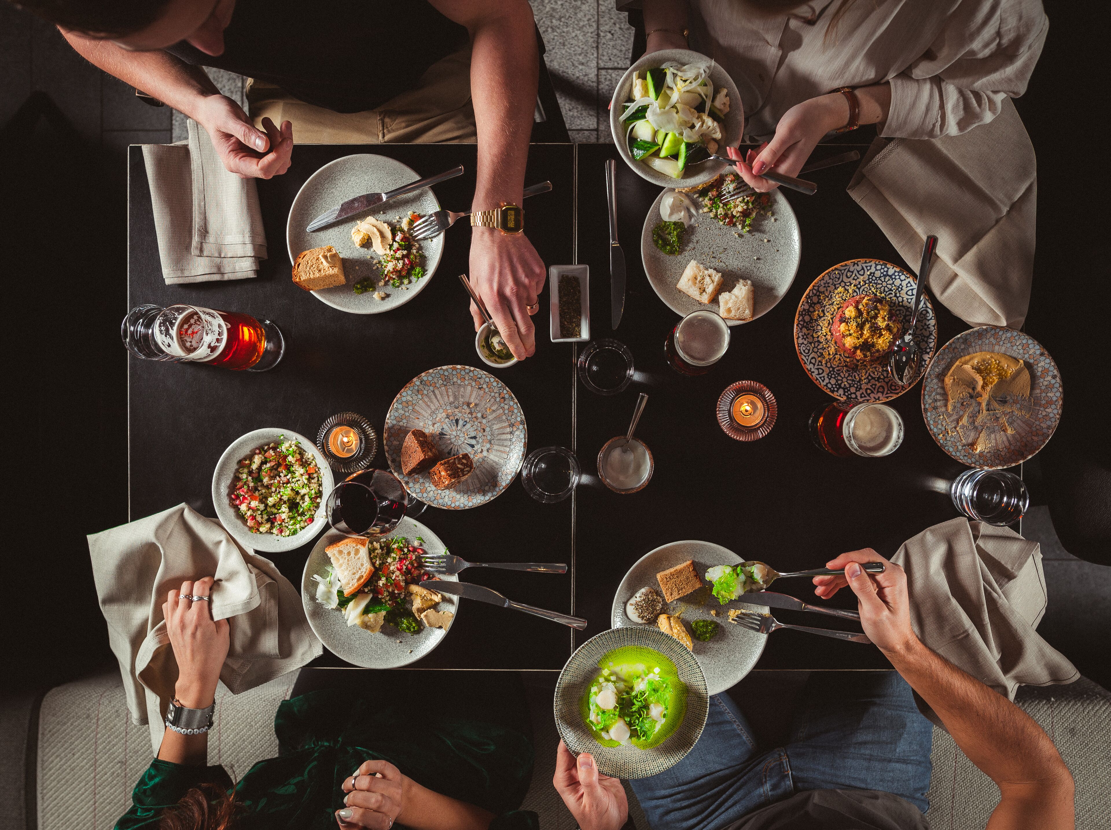 A group of people dining at a table with various dishes, glasses, and cutlery.