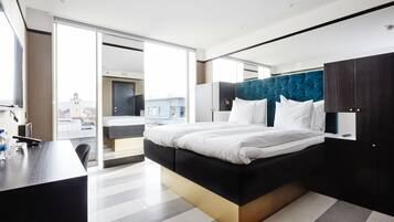 Una habitación de hotel moderna con una cama grande, un escritorio y vistas a la ciudad a través de la ventana.