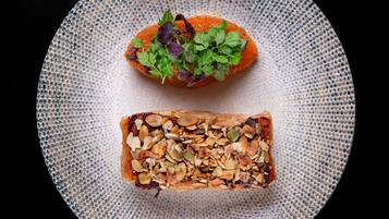 Un plato con una rebanada de pan cubierta de nueces y un trozo de salmón con hierbas.