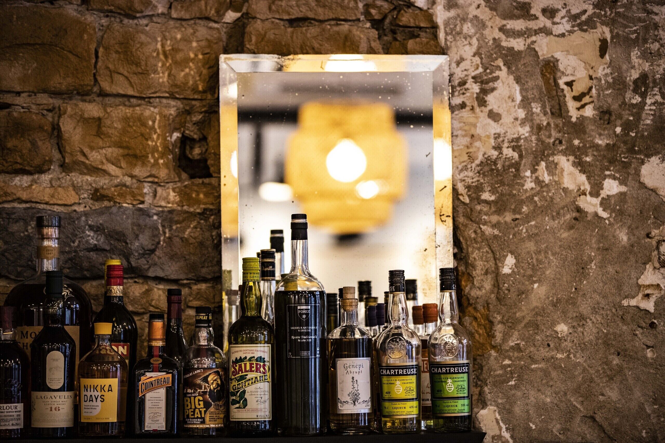Un bar con varias botellas de licor exhibidas frente a una pared de piedra.