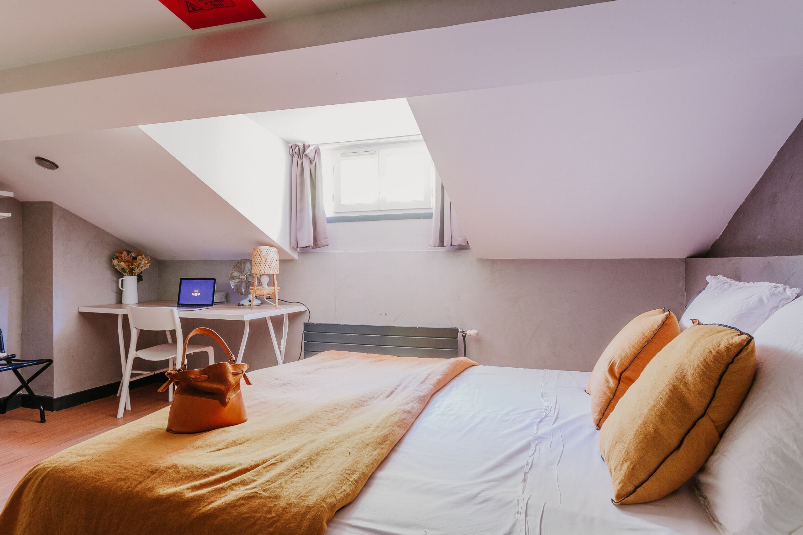 Una camera da letto con un letto, una scrivania con un portatile, una sedia e una finestra con tende.