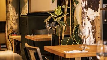 Un interior de restaurante con mesas y sillas de madera y una planta.
