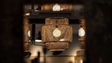 Gros plan d’un luminaire suspendu, fait de métal tissé, qui diffuse une lumière chaleureuse.