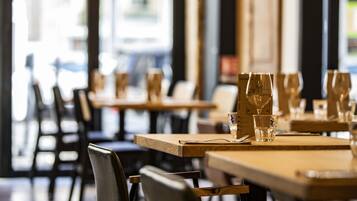 Un interior de restaurante con mesas y sillas de madera, vasos colocados sobre cada mesa y un menú en la mesa.