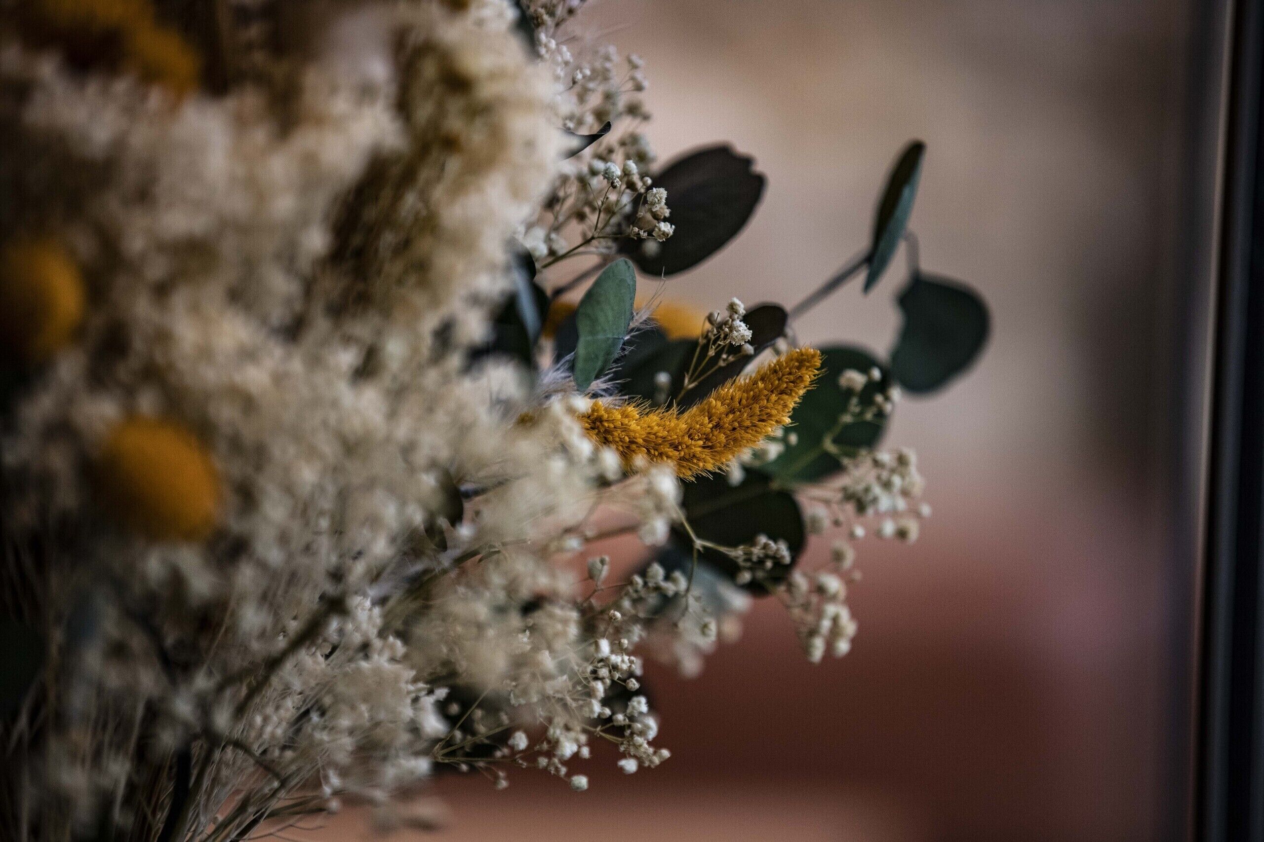 A close-up of a floral arrangement with dried flowers and greenery.