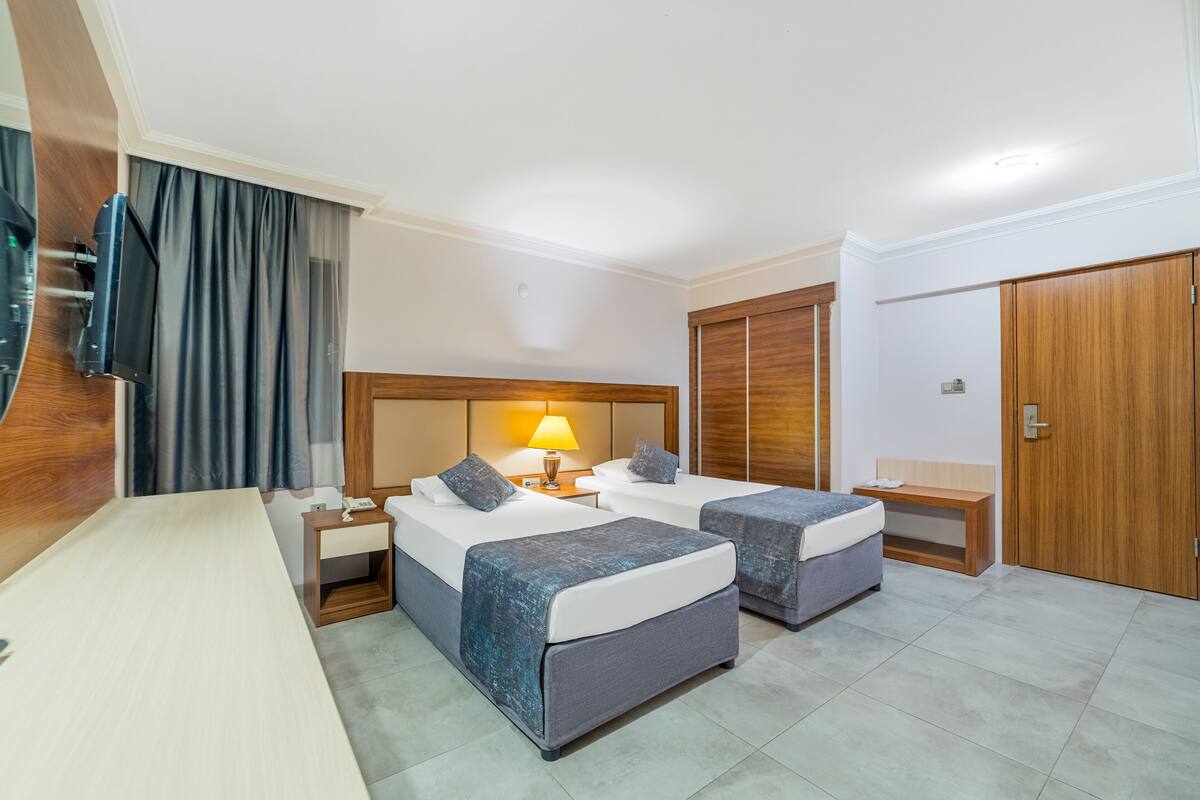 Une chambre d’hôtel avec deux lits, un bureau, une télévision et une armoire.