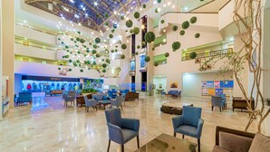 A spacious lobby with multiple seating areas, a high ceiling with hanging lights, and a visible staircase. - Justiniano Park Conti (Alanya)