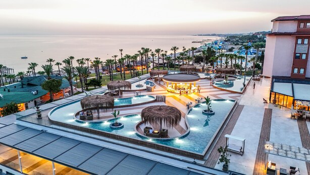 A resort pool area with multiple pools, lounge chairs, and a bar area. - Justiniano Park Conti (Alanya)
